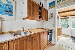a kitchen with wooden cabinets and a sink at 10054-Rorvig-Lindegardsvaenget-27 in Rørvig +13 photos