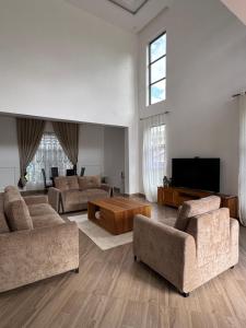 a living room with two couches and a tv at Kili Maisha Grand Home in Moshi