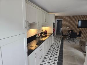 a kitchen with white cabinets and a black and white tile floor at Dunderry Lodge Luxury Suites in Navan