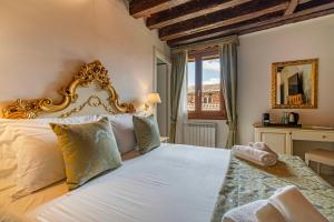 a bedroom with a white bed with a gold frame at Rialto Charm Boutique in Venice