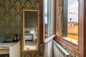 a mirror in a room with a bed and a window at Rialto Charm Boutique in Venice