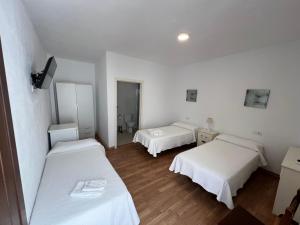 two beds in a room with white walls and wooden floors at Hostal Rios in Bolonia