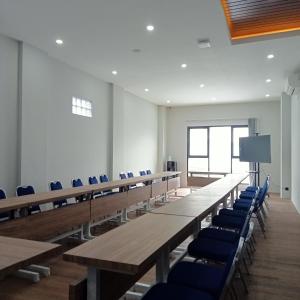 a conference room with wooden tables and blue chairs at NH Residence Yogyakarta in Ngabean