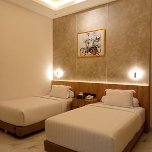 a hotel room with two beds and a painting on the wall at NH Residence Yogyakarta in Ngabean +7 photos