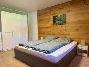 a bedroom with a bed with a wooden wall at Ferienwohnung Sattler in Mistelgau