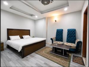 a bedroom with a bed and two chairs and a table at AGH Guesthouse & Rooms in Islamabad
