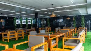 a restaurant with wooden tables and chairs and green grass at Ocean Front Hotels Enugu in Awkuzu
