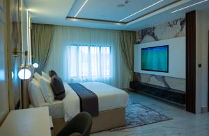 a hotel room with a bed and a flat screen tv at Ocean Front Hotels Enugu in Awkuzu
