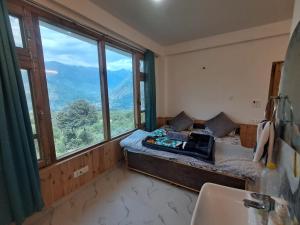 a bedroom with a bed and a large window at Nashala View Homestay in Nagar