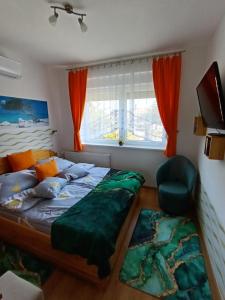 a bedroom with a bed and a chair and a window at Riviera Apartman in Hajdúszoboszló