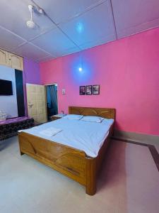 a bed in a room with a pink wall at The Cloud9 Villa in Tezpur