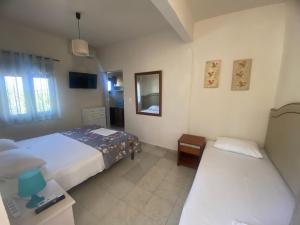a bedroom with two beds and a mirror at Eleftheria House in Vourvourou