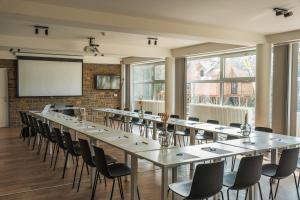 a row of tables and chairs in a room with a projection screen at Mont-des-Pins in Durbuy