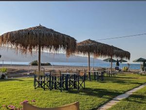 a group of tables and chairs under umbrellas on the beach at Villa Marcella by the Sea in Kamisianá
