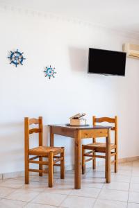 a dining room table with two chairs and a television at Giota's Studio in Karpathos