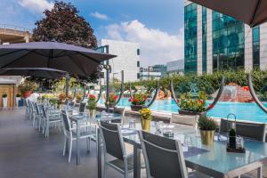 a restaurant with tables and chairs and a pool at iH Hotels Milano Lorenteggio in Milan