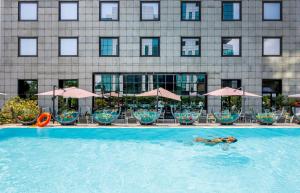 a person swimming in a pool in front of a hotel at iH Hotels Milano Lorenteggio in Milan