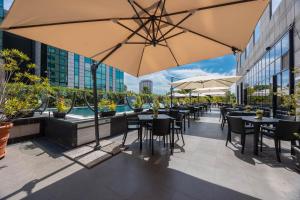 a patio with tables and umbrellas on a building at iH Hotels Milano Lorenteggio in Milan