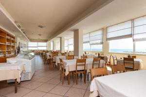 a dining room with tables and chairs and windows at Hotel Man in Lido di Savio