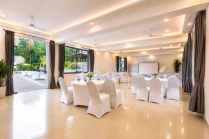 a banquet hall with white tables and white chairs at The Blossom Resort - Chikmagalur in Chikmagalūr +77 photos