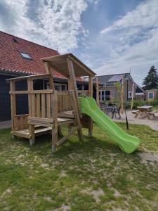 a playground with a green slide in a yard at Granny's B&B in Kapelle