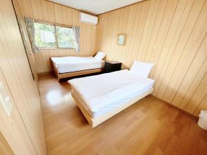 two beds in a room with wooden walls and wood floors at 田園の宿 in Takehanachō