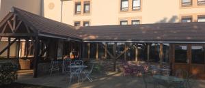 a patio with tables and chairs and a building at Hôtel Ikar Blois Sud in Saint-Gervais-la-Forêt