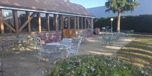 a group of tables and chairs in front of a building at Hôtel Ikar Blois Sud in Saint-Gervais-la-Forêt