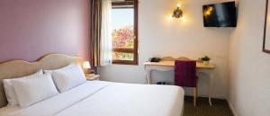 a hotel room with a bed and a desk and a window at Hôtel Ikar Blois Sud in Saint-Gervais-la-Forêt