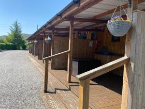 a wooden building with a porch with a basket of flowers at Cosy Glamping In the Eskdale Valley - Studio Lodges and Mega Pods in Eskdale