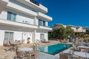 a hotel with a swimming pool and tables and chairs at Vila Antonio in Ksamil