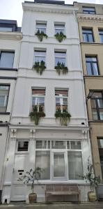 a white building with windows and potted plants on it at Sint Andries Suites in Antwerp