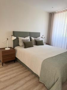 a bedroom with a large bed and a table with a lamp at Vila Sotto Mayor in Figueira da Foz