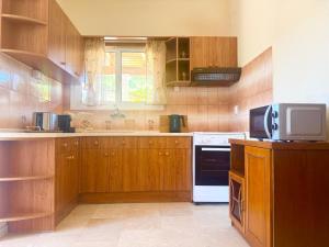 a large kitchen with wooden cabinets and a microwave at TETRAKTYS ESTATE beachside seaview ΥΔΩΡ with big garden in Halikounas +71 photos