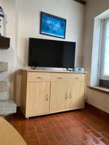 a flat screen tv on top of a wooden cabinet at "Les Mouettes" Maison de pêcheur en centre ville in Saint-Vaast-la-Hougue