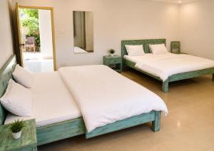 two beds with white sheets in a room at Sky Mount Villa in Mount Ābu