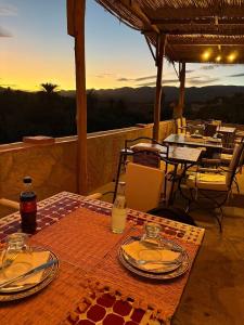a wooden table with plates and drinks on a patio at Kasbah Petit Nomade in Tinerhir