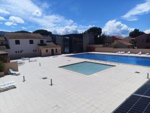 a large swimming pool in a courtyard with a building at Bleu miami in Argelès-sur-Mer