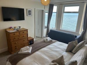 a bedroom with a bed and a dresser with a television at Awel Mor in Criccieth