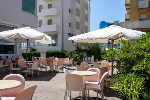 an outdoor patio with tables and chairs and umbrellas at Hotel Man in Lido di Savio