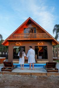 a man and woman standing in front of a house at Cabanha Sítio Gomes in Canoinhas