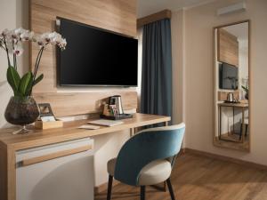 a room with a desk with a television and a chair at Hotel Livata Mountain Wellness in Subiaco