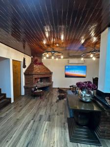 a living room with a brick fireplace and a table with flowers at Cabanha Sítio Gomes in Canoinhas