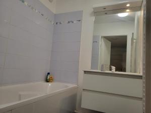 a white bathroom with a tub and a mirror at 1 chambre double privée et securisée dans un appart avec espace partagé in Saint-Denis