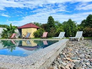 a swimming pool with chairs and a house at Villa Jakos Paradise in Batumi
