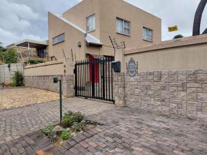 a house with a black gate and a brick wall at Naomi's Sky Loft Little Falls in Roodepoort