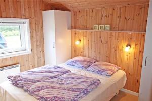 a bed in a room with wooden walls and a window at LF15018-Skals-Lynderup-Strand-4 in Skals