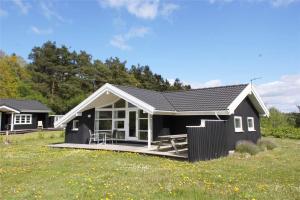 a small black house with a porch in a field at LF15018-Skals-Lynderup-Strand-4 in Skals