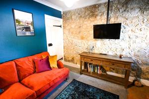 a living room with an orange couch and a tv at Stade Cottage in Hythe