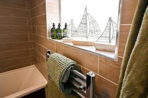 a bathroom with a shelf with three bottles of wine at Stade Cottage in Hythe +26 photos